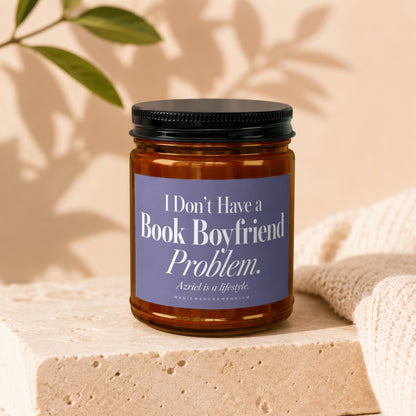 Amber glass candle jar with a black lid and purple label featuring book-themed white text.