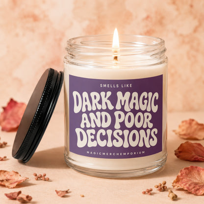 Jar candle with lit wick and purple label reading "Smells Like Dark Magic and Poor Decisions."