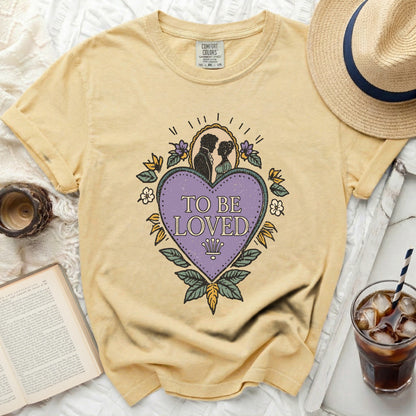 Yellow t-shirt with "To Be Loved" graphic and romantic couple silhouette