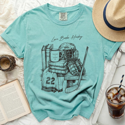 Teal t-shirt with sketch of hockey gear, books, and "Love Books. Hockey." text.