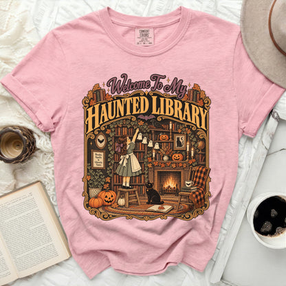 Pink Comfort Colors t-shirt with "Welcome To My Haunted Library" Halloween graphic.