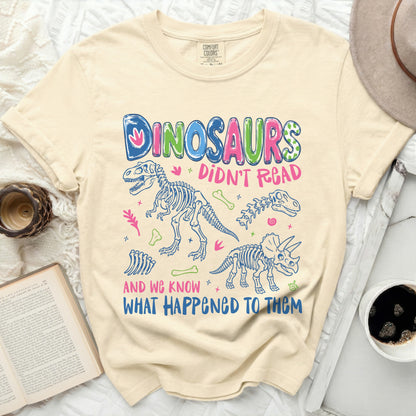 Cream t-shirt with "DINOSAURS DIDN'T READ AND WE KNOW WHAT HAPPENED TO THEM" graphic.