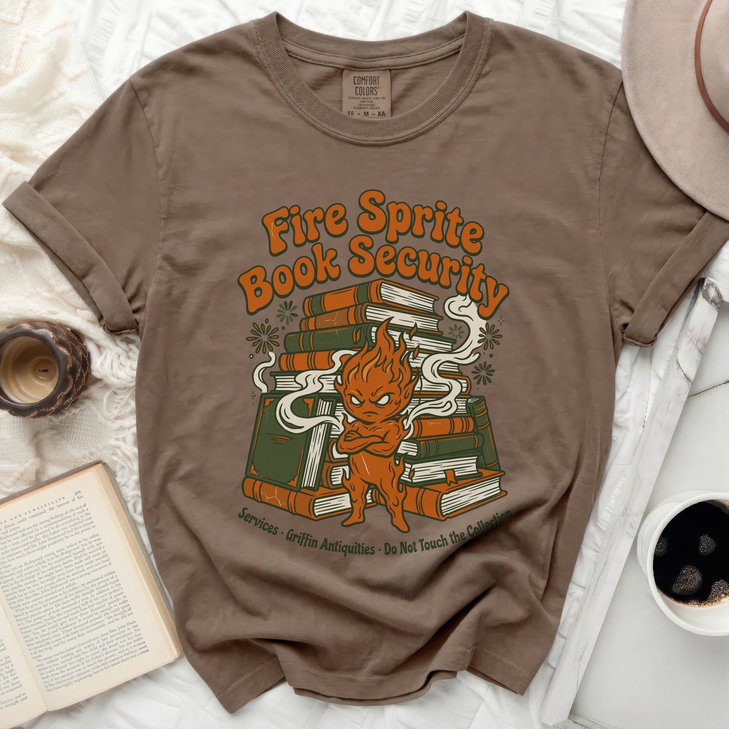 Brown t-shirt with a cartoon fire sprite and pile of books graphic.