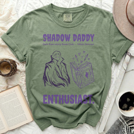 Green t-shirt with "Shadow Daddy" text and illustrated book.