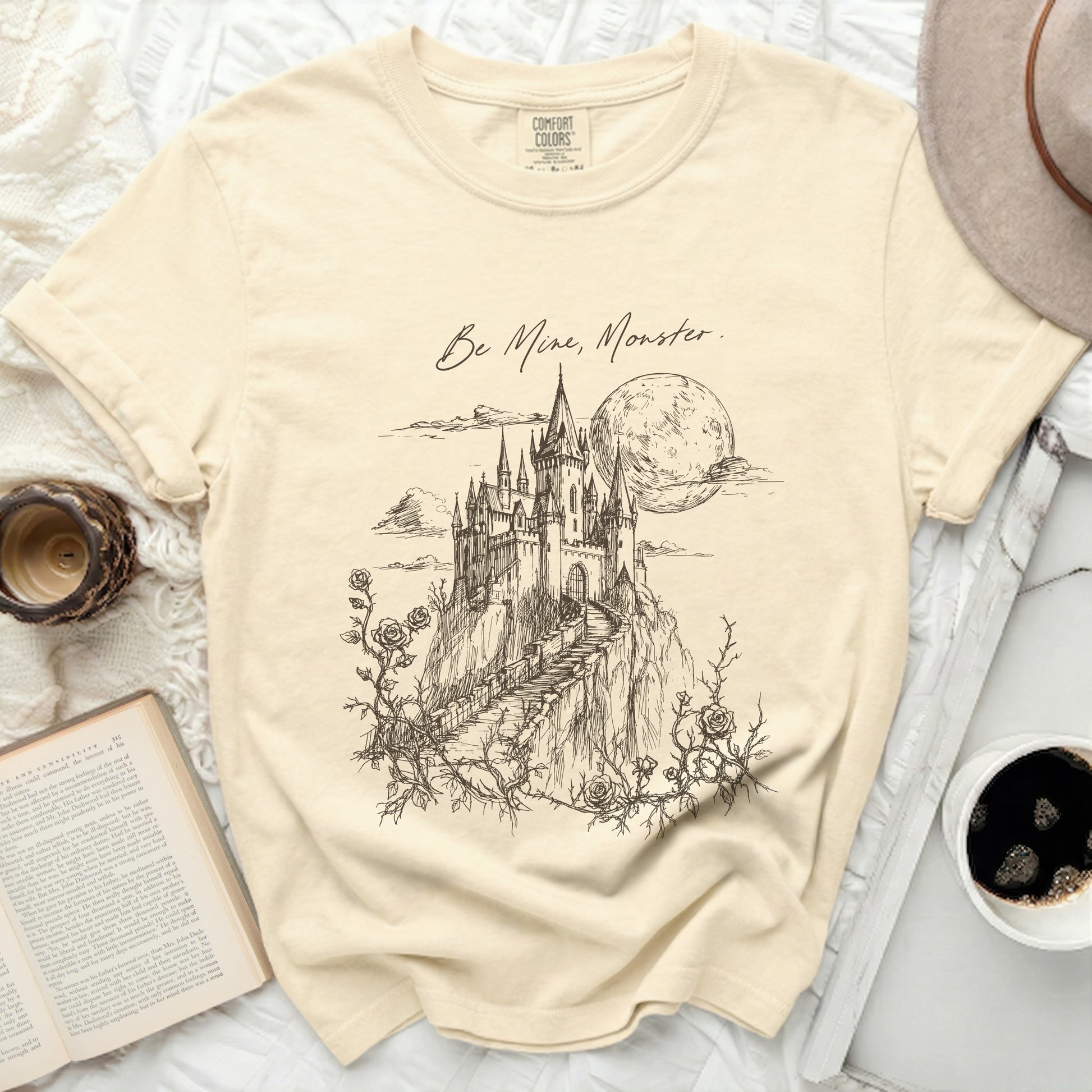 Cream t-shirt with "Be Mine, Monster." text and castle sketch.