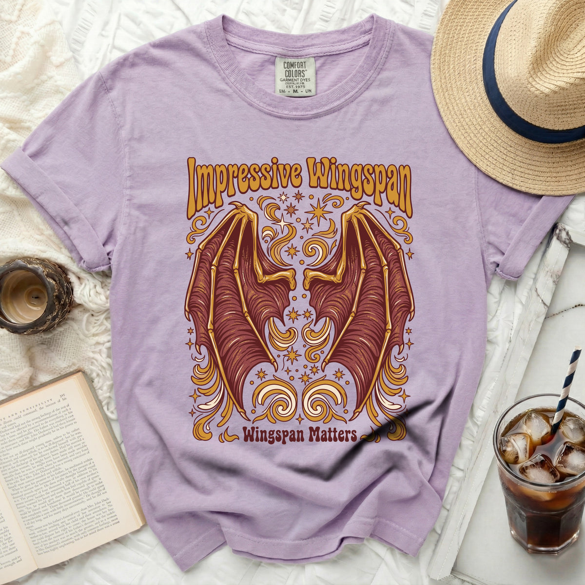 Lilac t-shirt with graphic of brown and gold wings and text "Impressive Wingspan" and "Wingspan Matters."