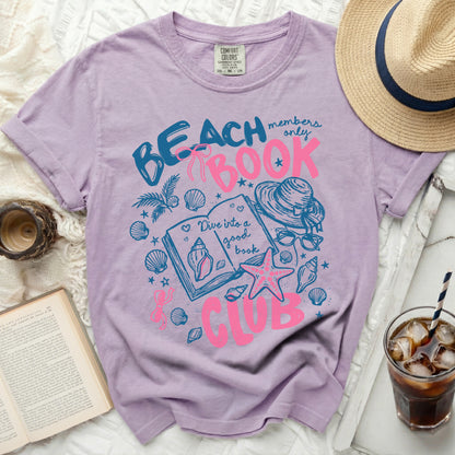 Purple t-shirt with "Beach Book Club" graphic featuring shells and a book.