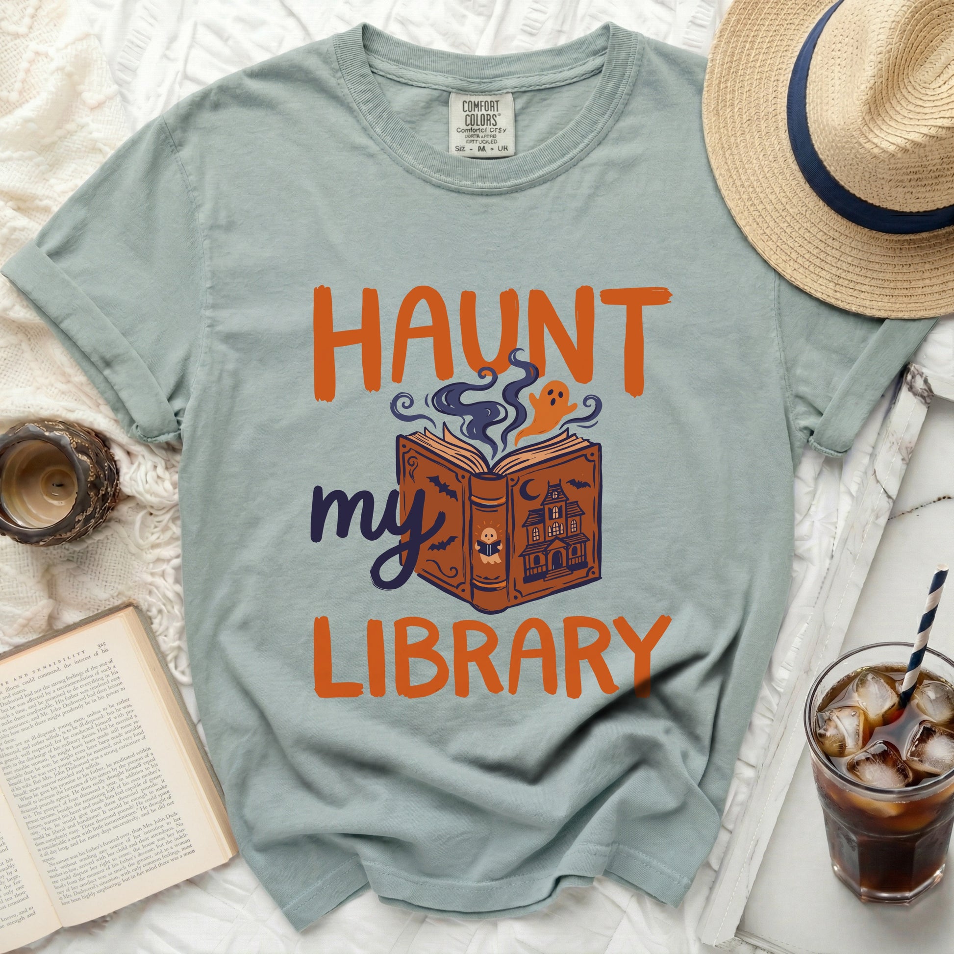 Light blue t-shirt with "Haunt my Library" graphic and ghost reading a book.