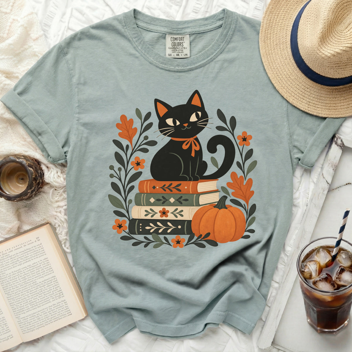 Black cat sitting on stack of books with pumpkin and floral accents.