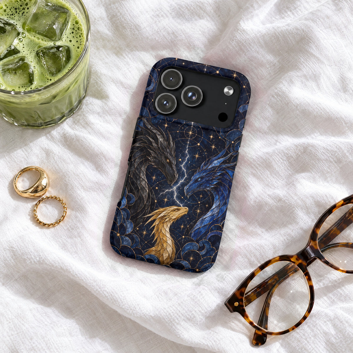 A dark blue phone case featuring three dragons and celestial patterns, resting on white fabric.
