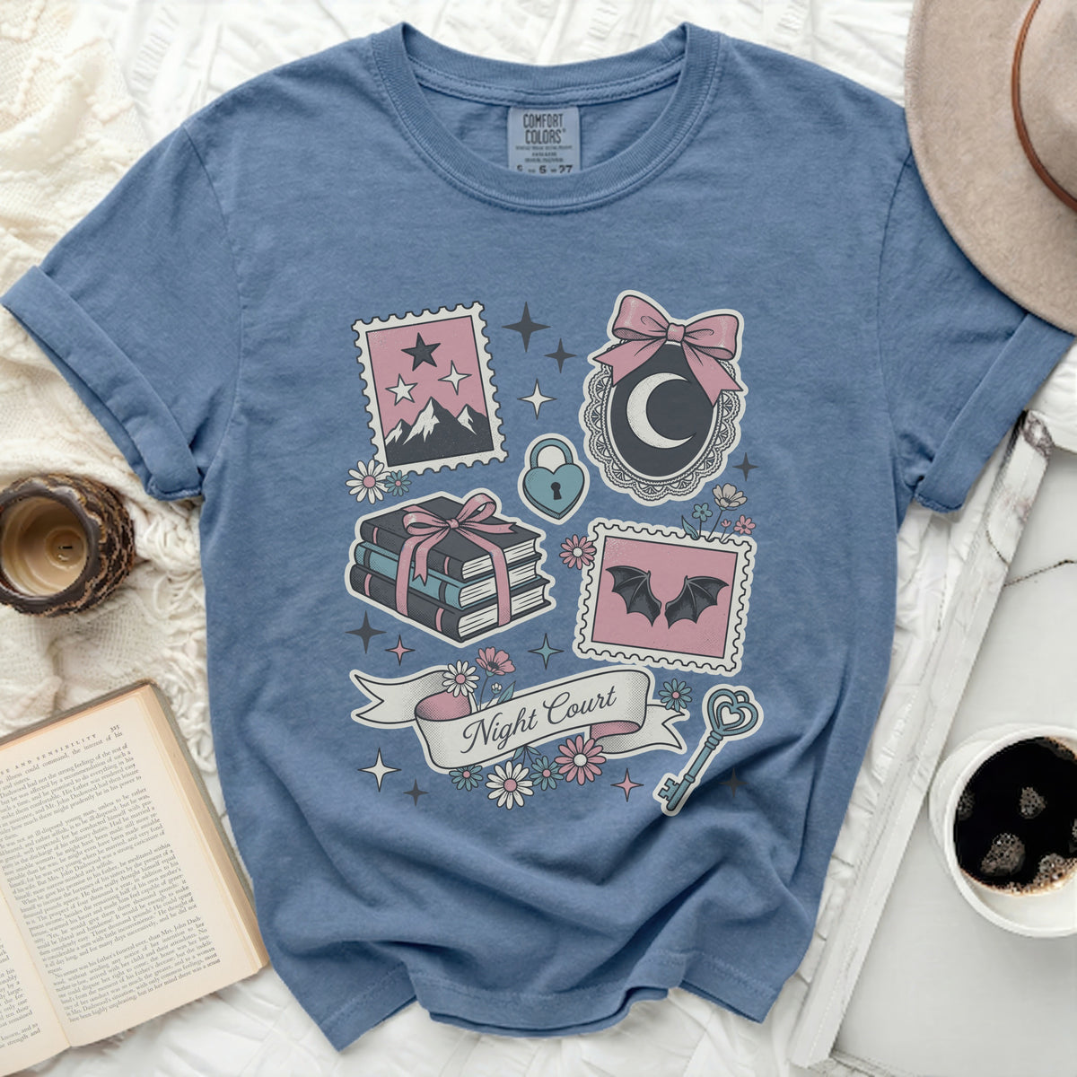 Blue t-shirt with pastel graphic of moon, books, bats, key, and "Night Court" text.