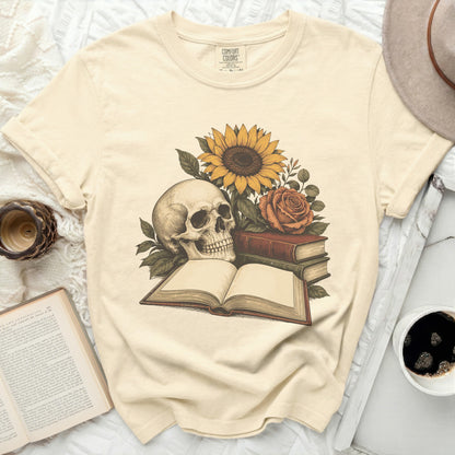 Skull, sunflower, rose, and books graphic on a cream t-shirt.