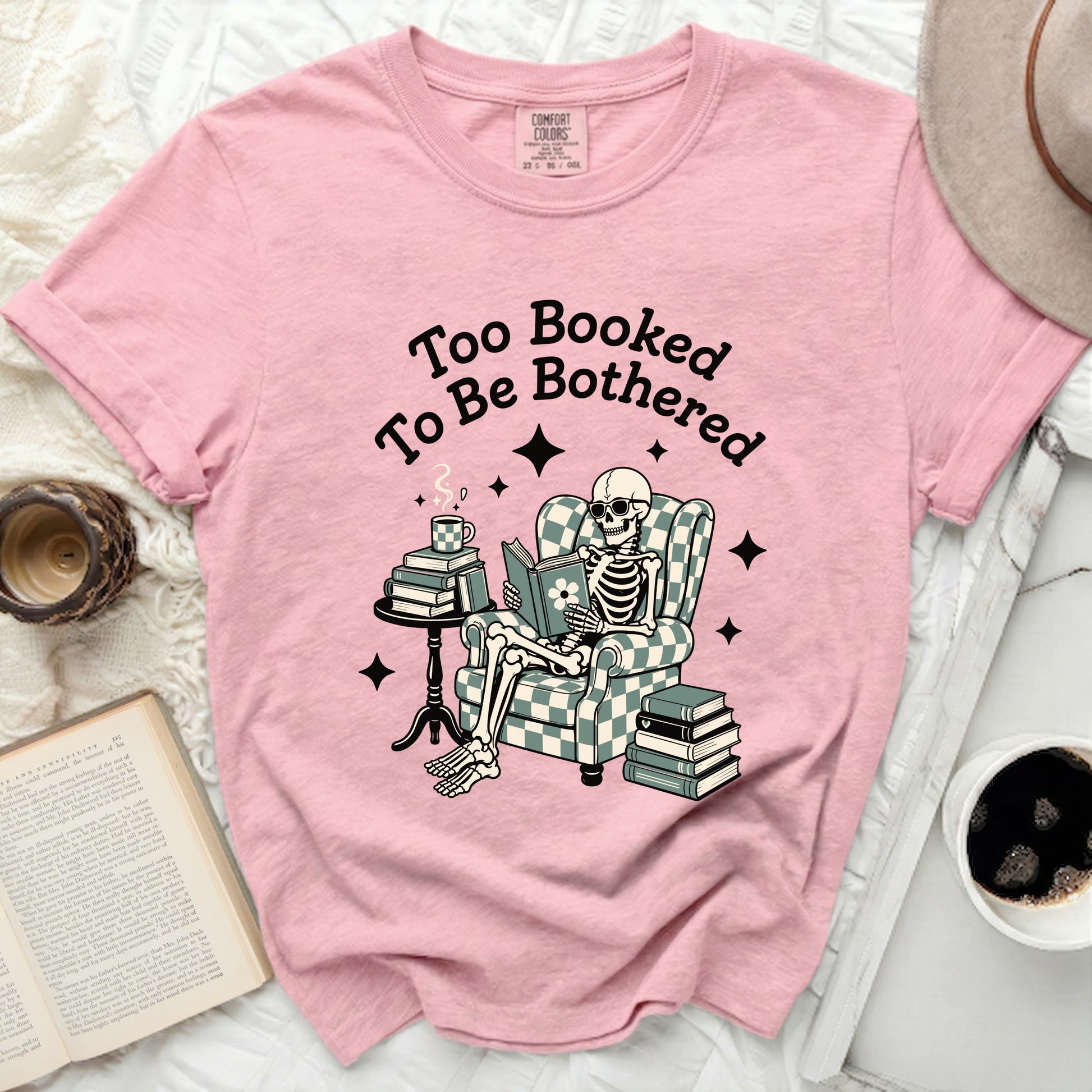 Pink t-shirt with "Too Booked To Be Bothered" and skeleton reading.