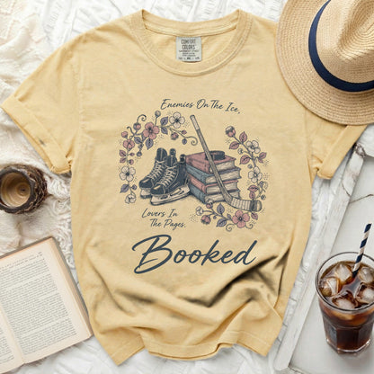 Yellow t-shirt with ice skates, hockey stick, books, and "Booked" text.