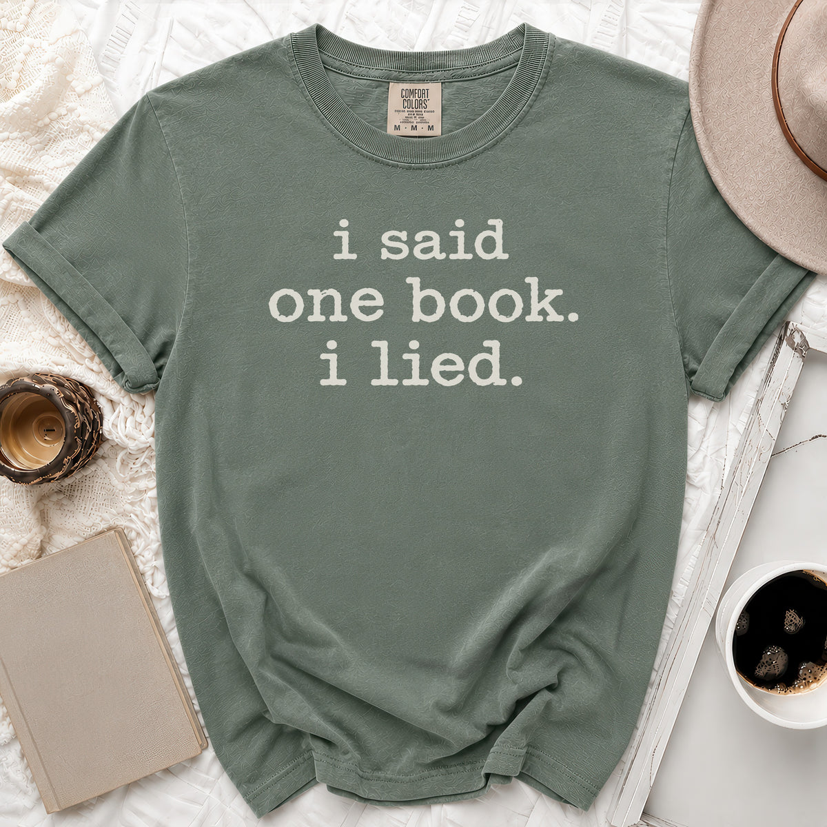 Sage green t-shirt with white text: "i said one book. i lied."