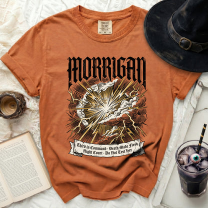 Orange t-shirt with Morrigan text, storm, lightning, and banner with quotes.