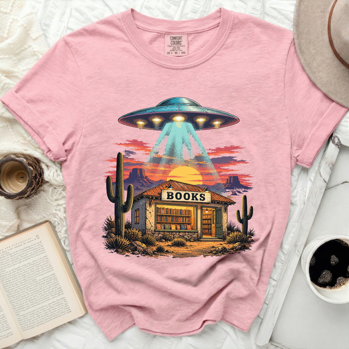 UFO over a desert bookstore with cactus and sunset.