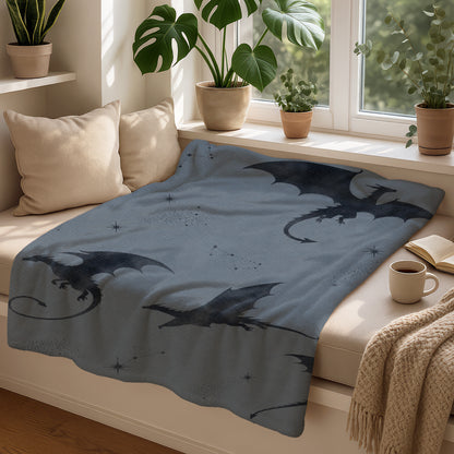 Blue blanket draped over a bench, featuring a dark grey dragon pattern with constellations.