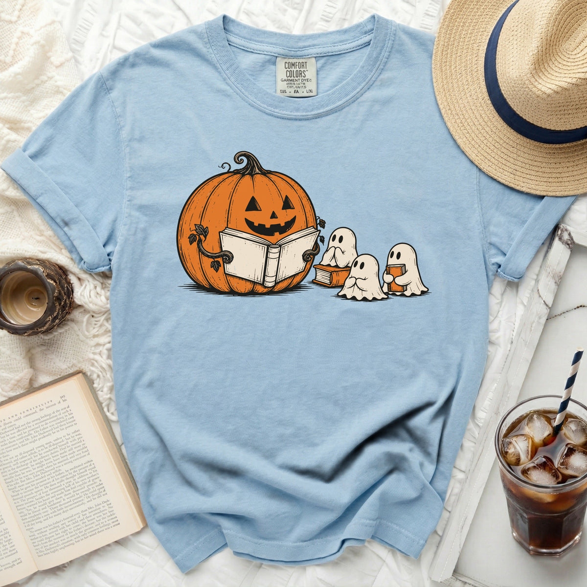 Light blue t-shirt with pumpkin and ghosts reading a book graphic.
