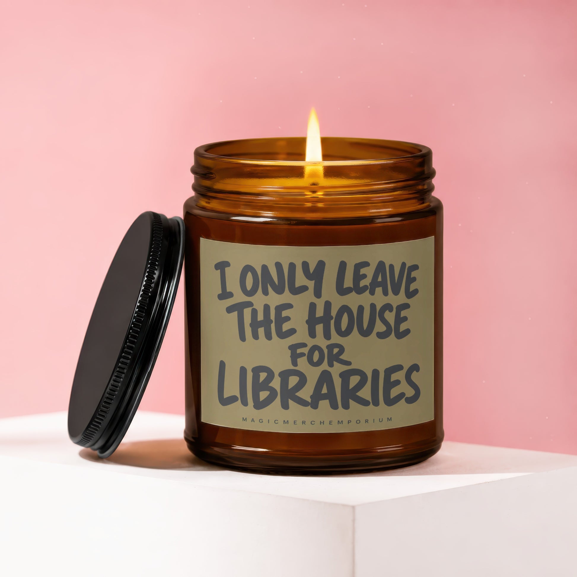 Lit candle in amber jar with black lid, text reads "I ONLY LEAVE THE HOUSE FOR LIBRARIES".