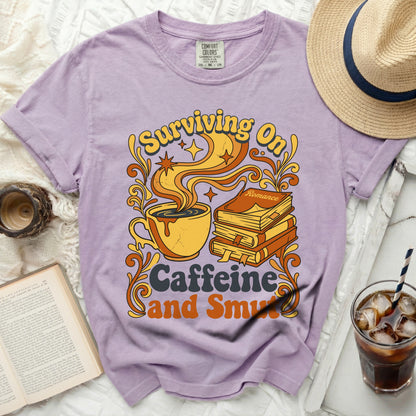 Purple t-shirt with "Surviving On Caffeine and Smut" graphic.