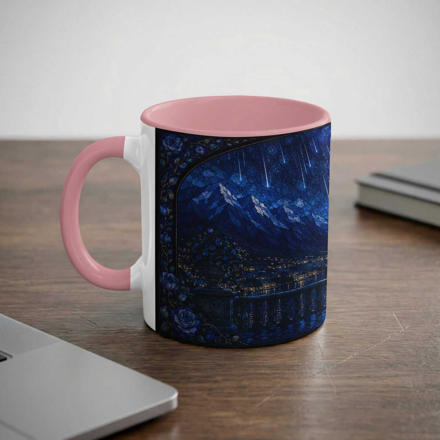 White mug with pink handle featuring a dark blue stained glass scene of mountains and a starry night.