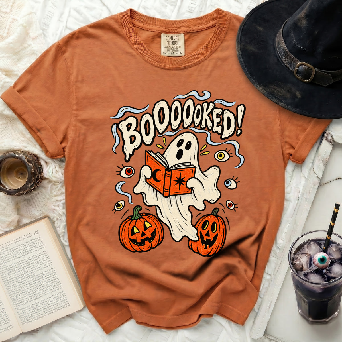 Orange t-shirt with ghost reading a book, pumpkins, eyes, and text "BOOOOOKED!".