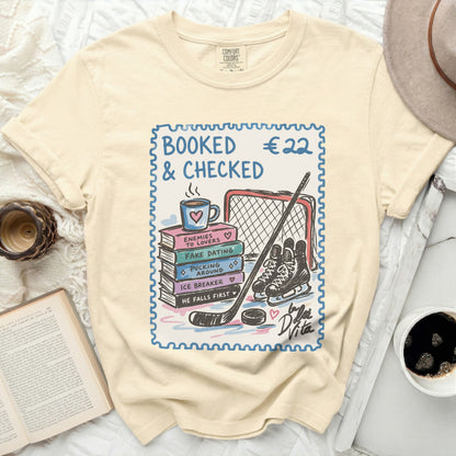 Cream t-shirt with "BOOKED & CHECKED" text and hockey theme.