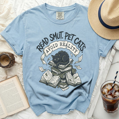 Light blue t-shirt with black cat on books and text "Read Smut. Pet Cats. Avoid Reality."