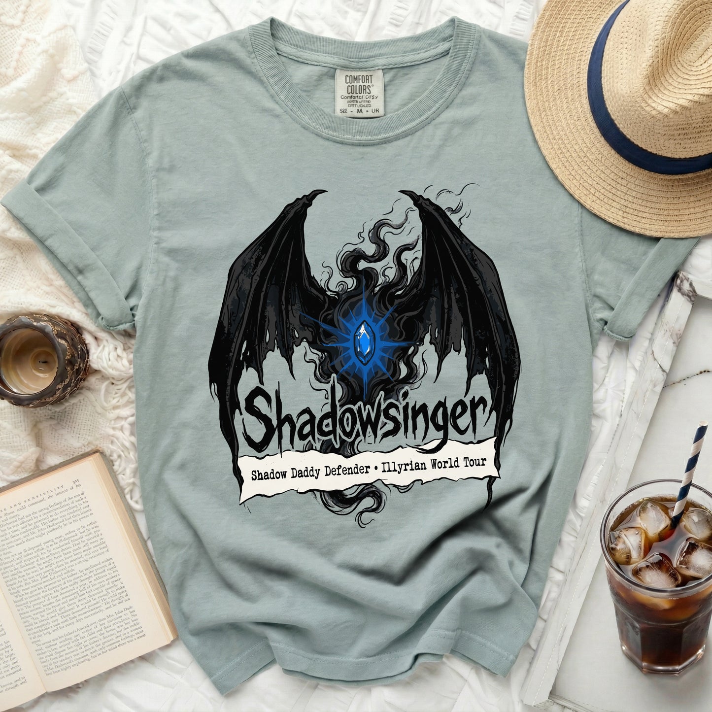 Light blue t-shirt with black bat wings, blue gem, and "Shadowsinger" text.