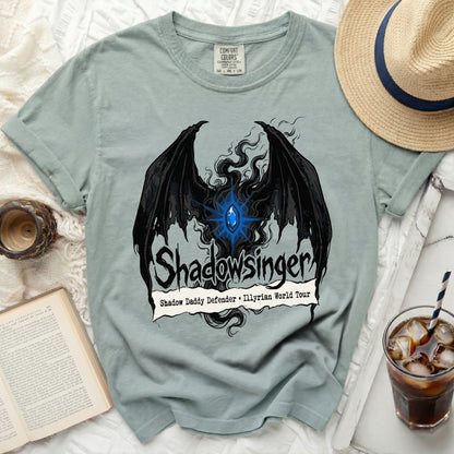 Light blue t-shirt with black bat wings, blue gem, and "Shadowsinger" text.