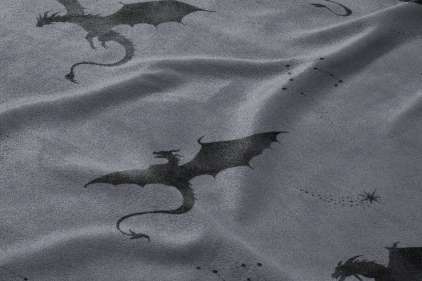 Dark gray fabric with a repeating pattern of silhouetted dragons and star constellations.