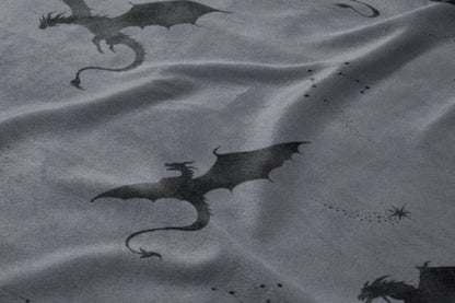 Dark gray fabric with a repeating pattern of silhouetted dragons and star constellations.