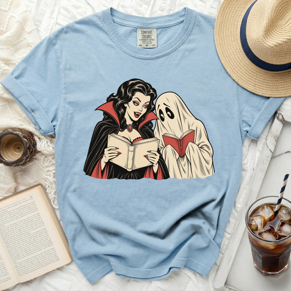 Light blue t-shirt with graphic of a vampire and ghost reading books.