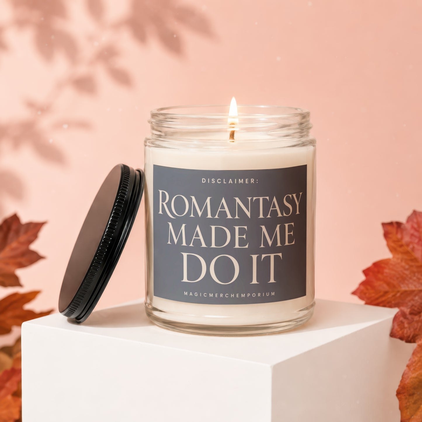 Lit candle with "ROMANTASY MADE ME DO IT" on label, with lid off.