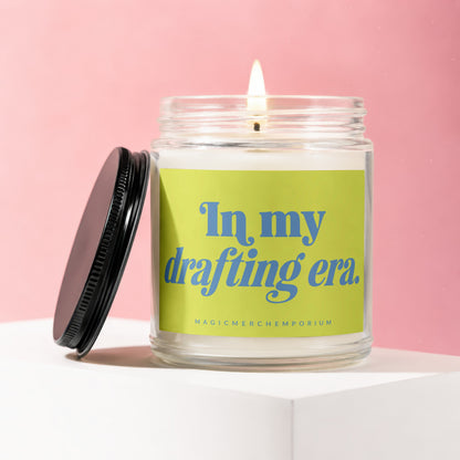 Jar candle with lit wick and black lid, labeled "In my drafting era."
