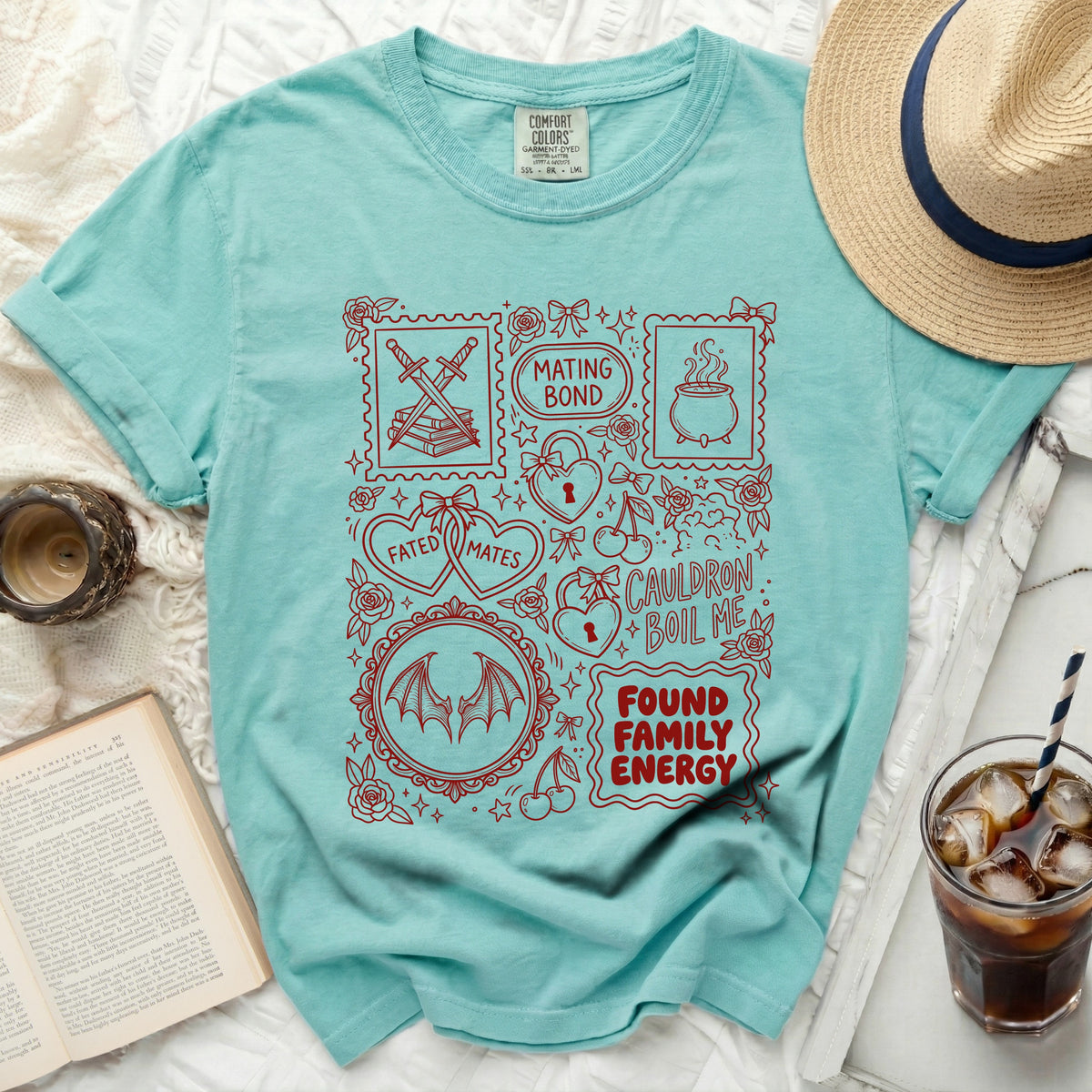 Teal t-shirt with red graphic design of swords, books, cauldron, hearts, and text.