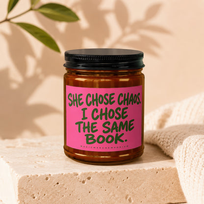 Candle with text "SHE CHOSE CHAOS. I CHOSE THE SAME BOOK."