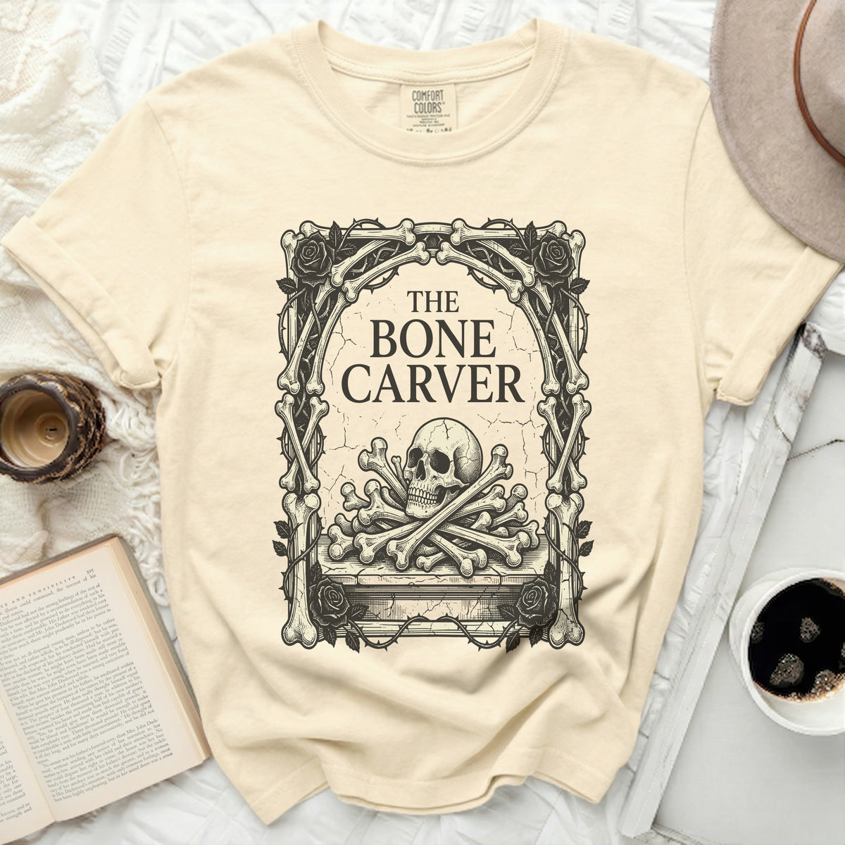 The Bone Carver graphic on a light yellow t-shirt with a skull and crossbones.