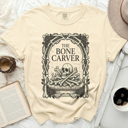 The Bone Carver graphic on a light yellow t-shirt with a skull and crossbones.