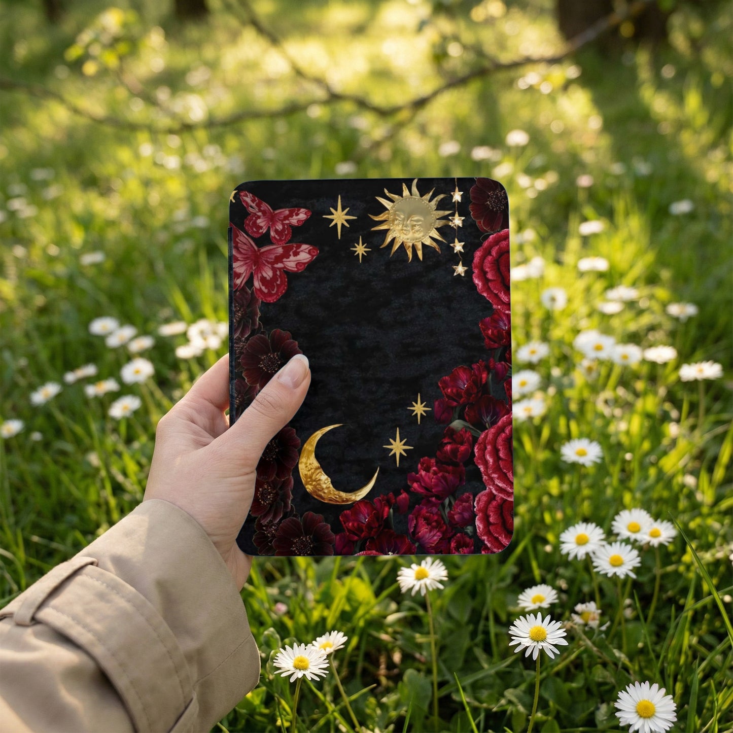 Black journal with celestial, floral, and butterfly design, held in a hand.