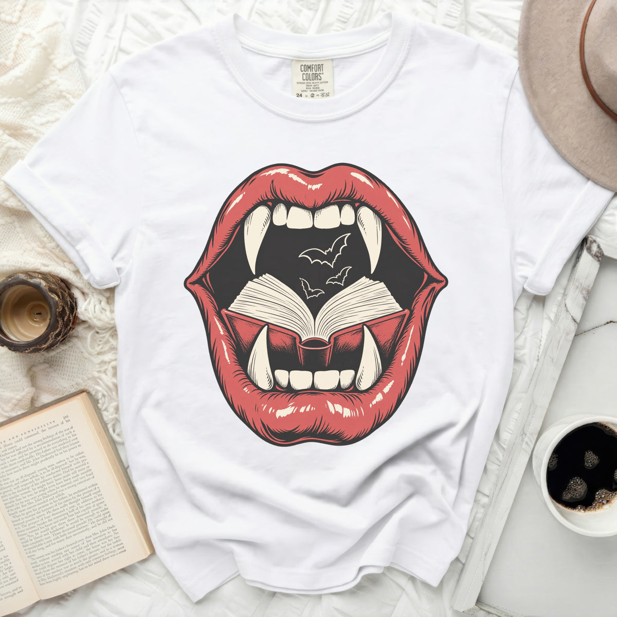 Graphic of red lips with fangs, open book, and bats on a white t-shirt.