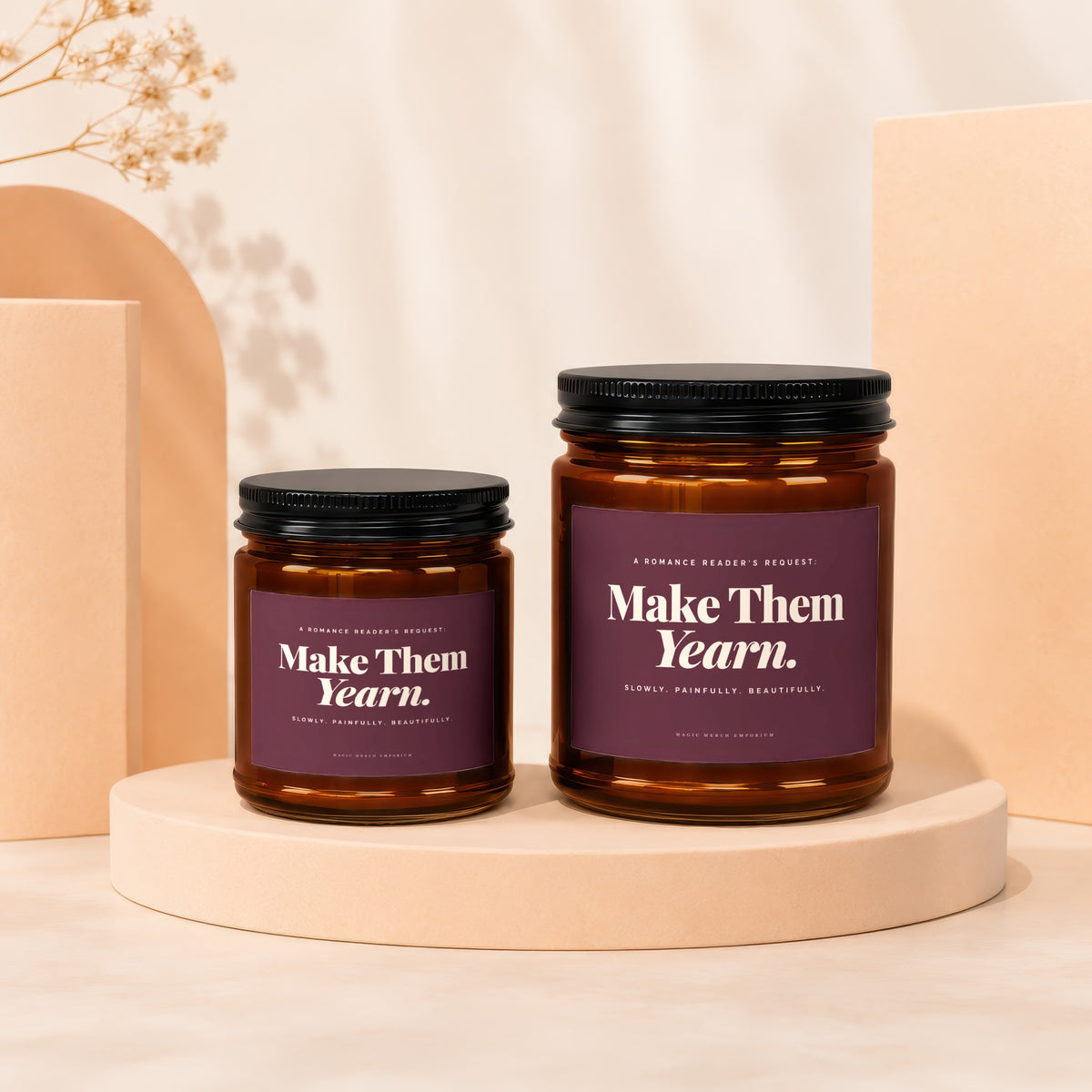 Two amber glass candles with dark lids and purple labels reading "Make Them Yearn."