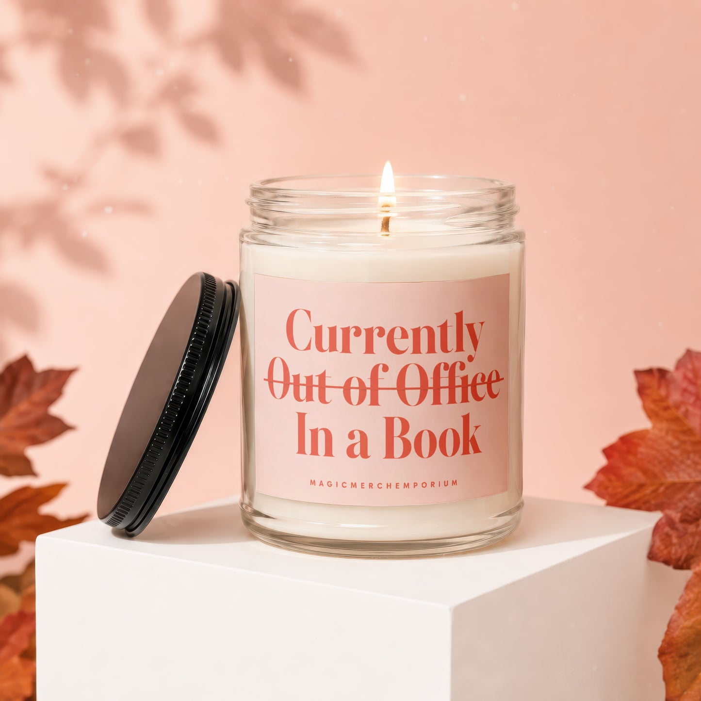 Candle with text "Currently Out of Office In a Book" and brand name.