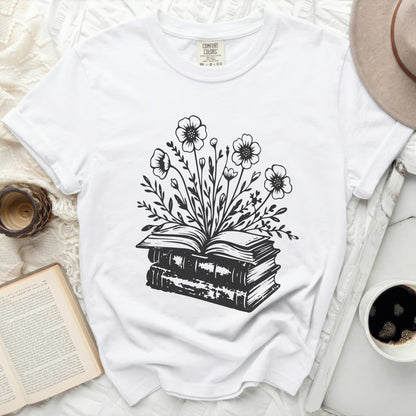 White t-shirt with black ink drawing of an open book crowned with flowers.