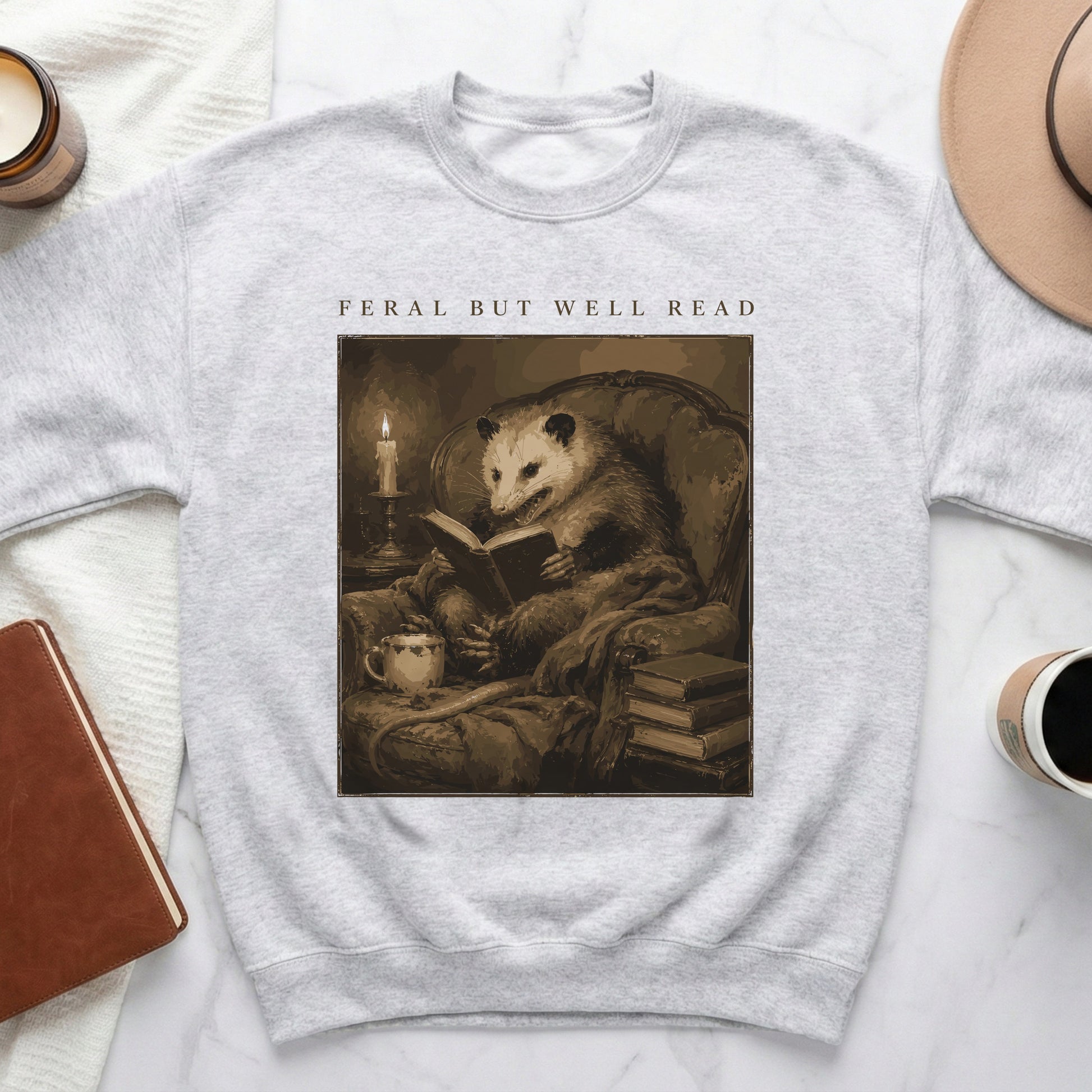 Opossum reading a book in armchair, text "Feral But Well Read" above.