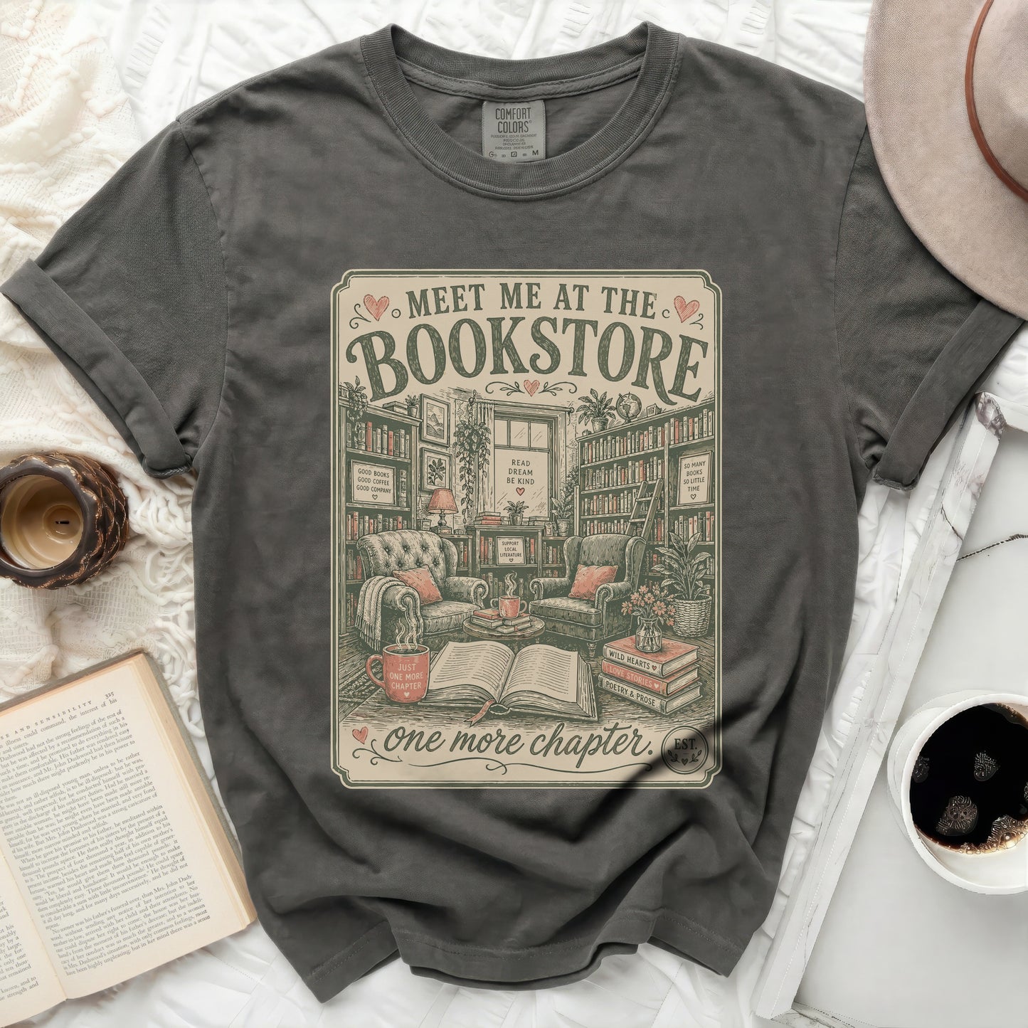 Graphic tee with "Meet Me at the Bookstore" text and cozy reading nook illustration.
