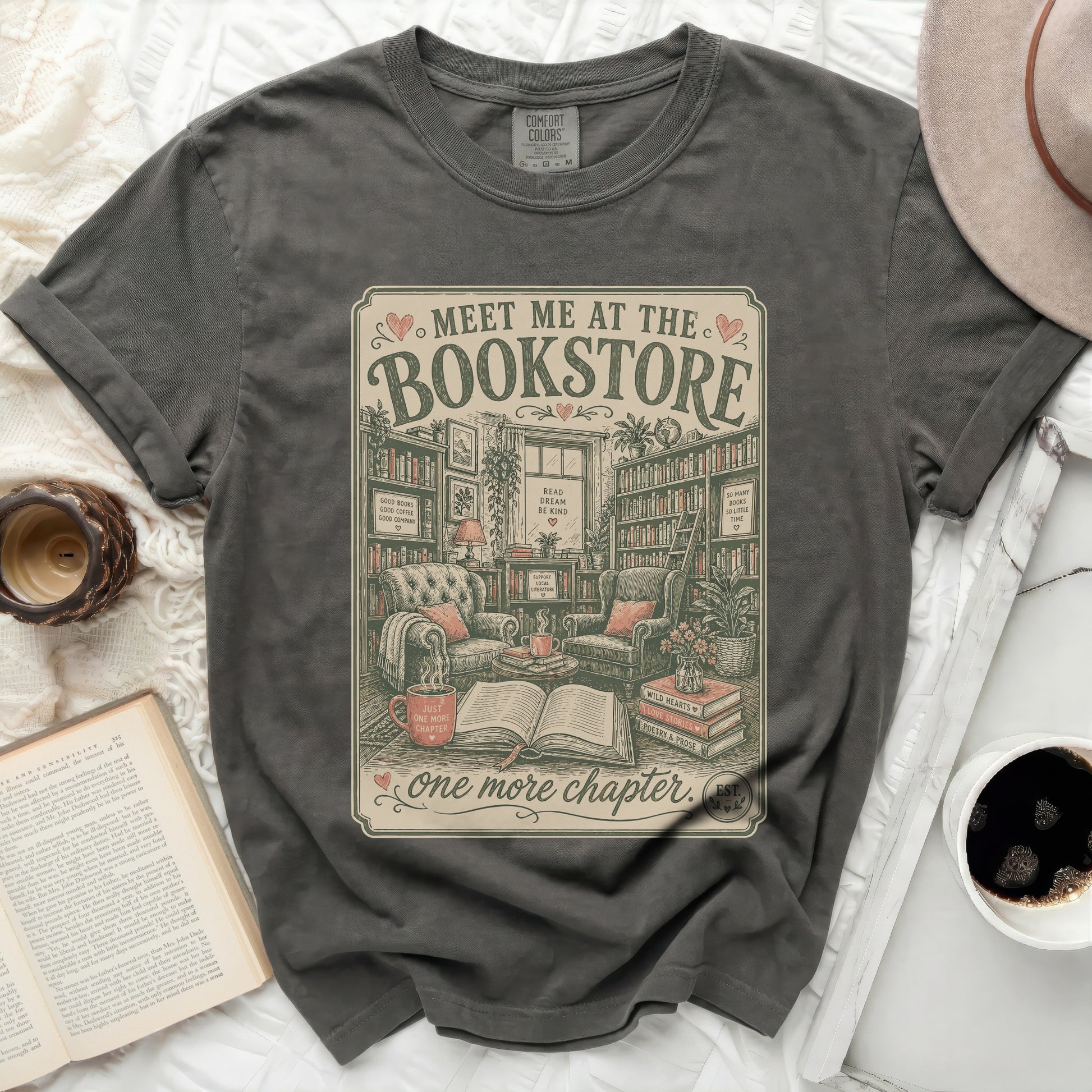 Graphic tee with "Meet Me at the Bookstore" text and cozy reading nook illustration.