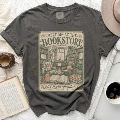 Graphic tee with "Meet Me at the Bookstore" text and cozy reading nook illustration.