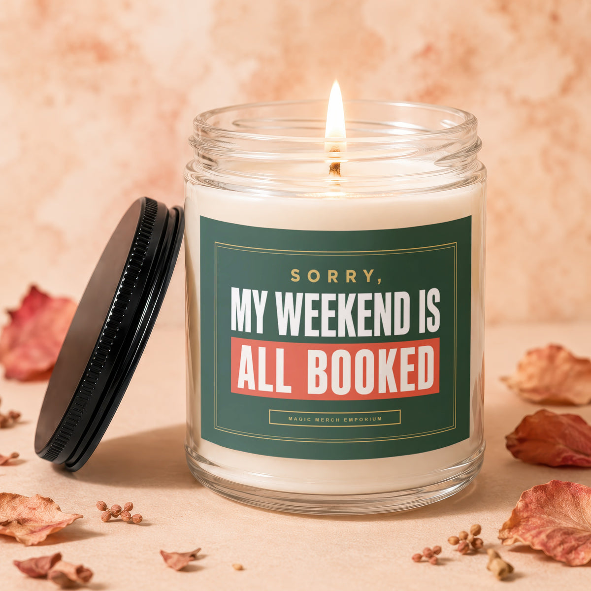 Candle with lid off, lit flame, reading "Sorry, My Weekend Is All Booked."